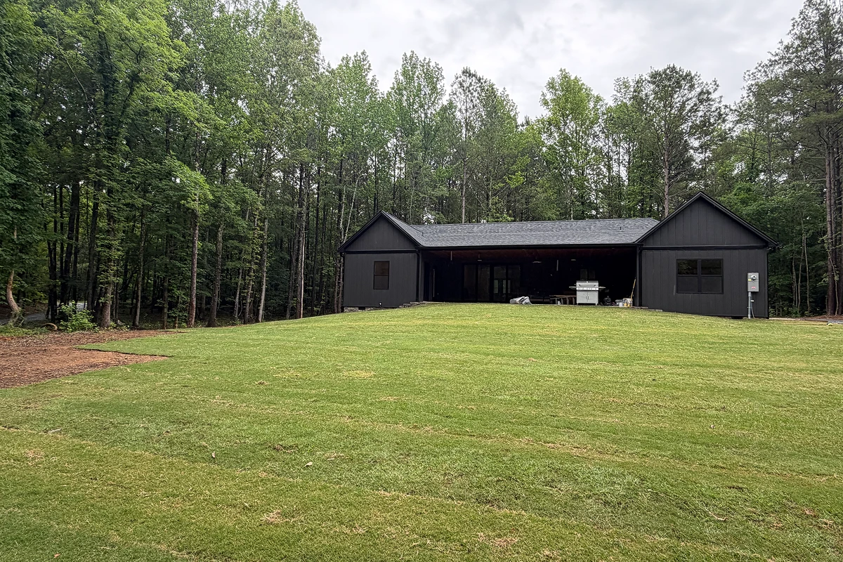 Dark cottage surrounded by dense forest.